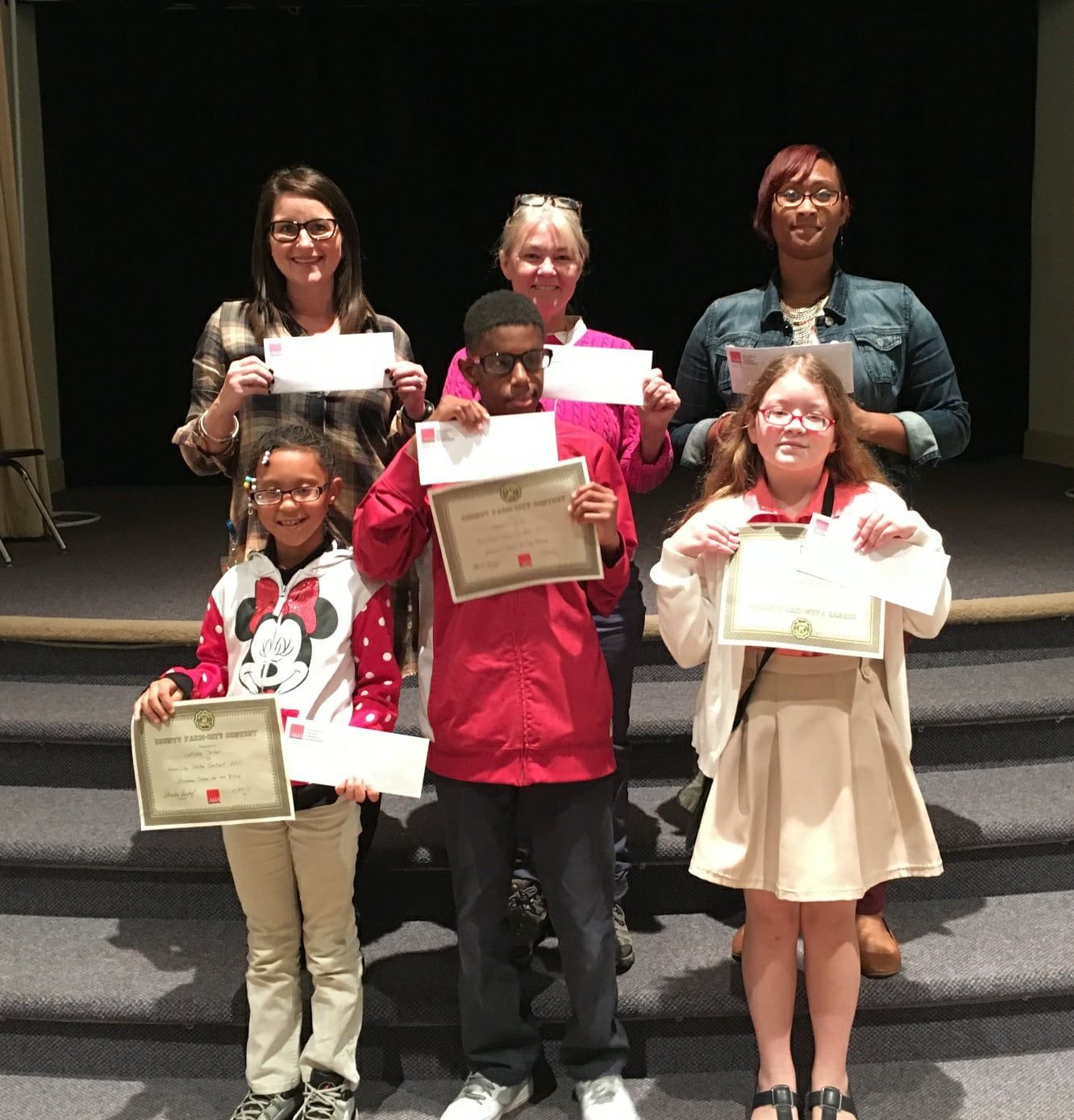 Students and teachers holding up checks they won from ALFA